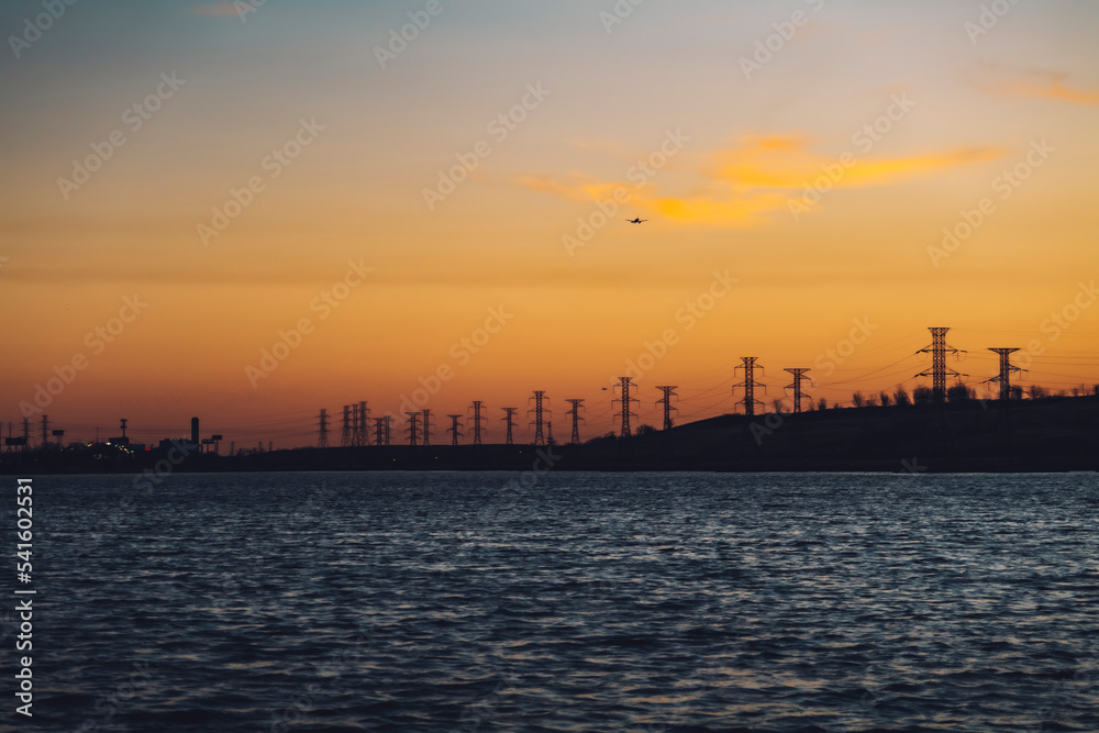 High voltage electricity tower sky sunset landscape, industrial background with water lake on front. High-quality photo