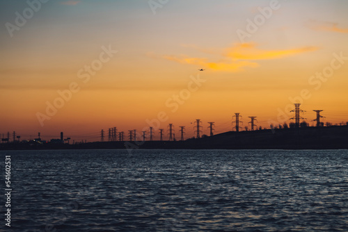High voltage electricity tower sky sunset landscape, industrial background with water lake on front. High-quality photo