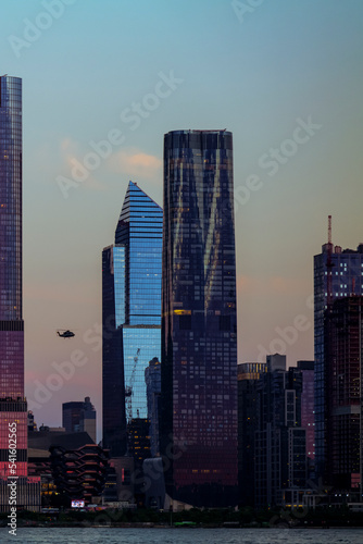 View to Manhattan skyline Hudson Yards skyscrapers and helicopter on the front, from Weehawken Waterfront in Hudson River at sunset. High quality photo