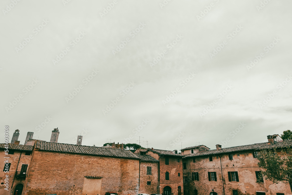 Old roofs of San Gimignano with cloudy sky background