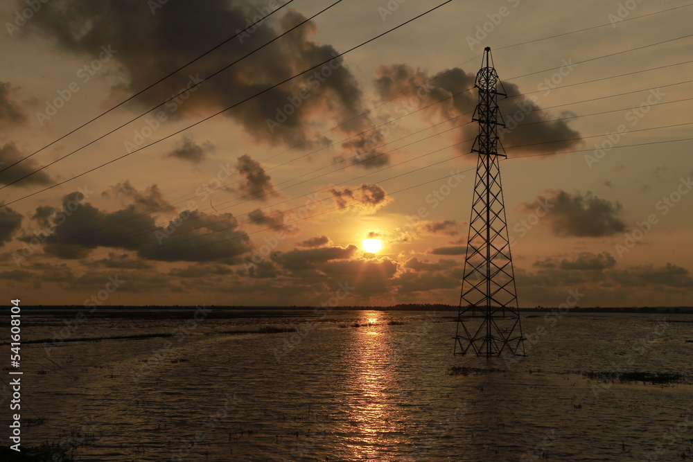 Sunset view from a lake side, powerlines passing above lake