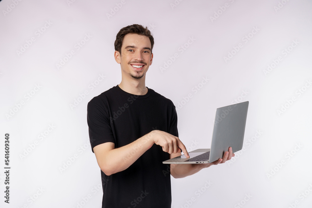 Portrait of young handsome smiling man holding laptop in hands, typing and browsing web pages isolated on white background Portrait of young handsome smiling man holding laptop in hands, typing and browsing web pages isolated on white background