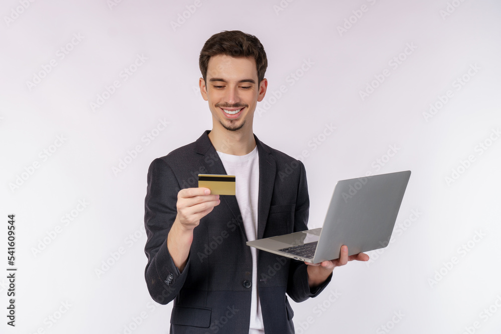 Portrait of young handsome smiling businessman holding creadit card and laptop in hands, typing and browsing web pages isolated on white background Portrait of young handsome smiling businessman holding creadit card and laptop in hands, typing and browsing web pages isolated on white background