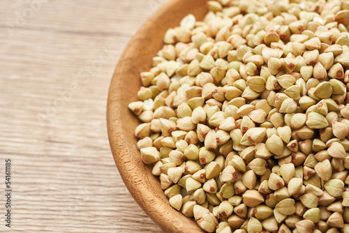 raw buckwheat seed in wood plate on wooden table background. buckwheat grain, buckwheat seeds 