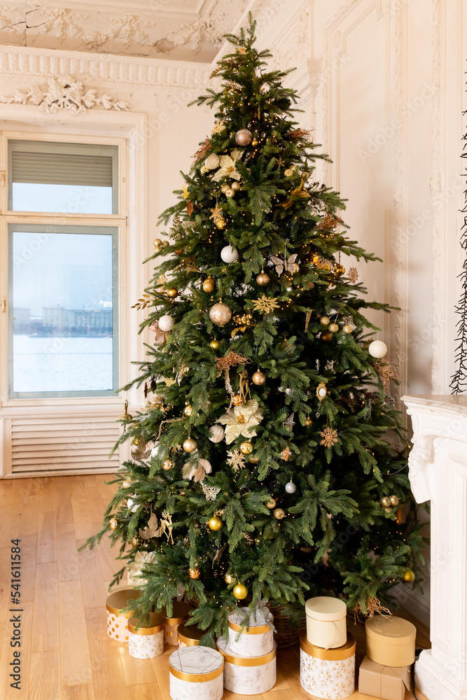 Decorated Christmas tree with golden patchwork ornament, gold balls and big gift presents for new year in living room, happy holidays Decorated Christmas tree with golden patchwork ornament, gold balls and big gift presents for new year in living room, happy holidays