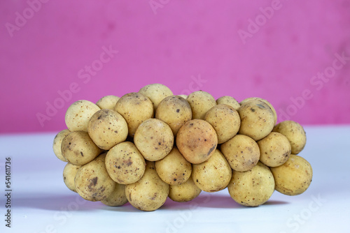 Longkong on a white table with a pink back. photo