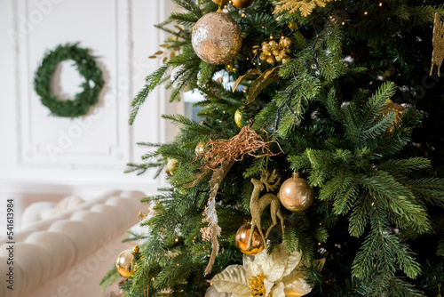 Christmas tree with vintage acorn and baubles with golden lights close up. Modern decorated christmas tree branches with stylish ornaments in festive room. Winter holidays, atmospheric time