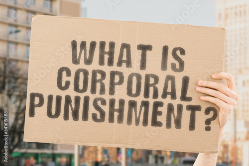 The question " What is corporal punishment? " is on a banner in men's hands with blurred background. Education. Teacher. Teenager. Boy. Person. Man. Afraid. Anger. Fear. Hitting. Sad. Obedience