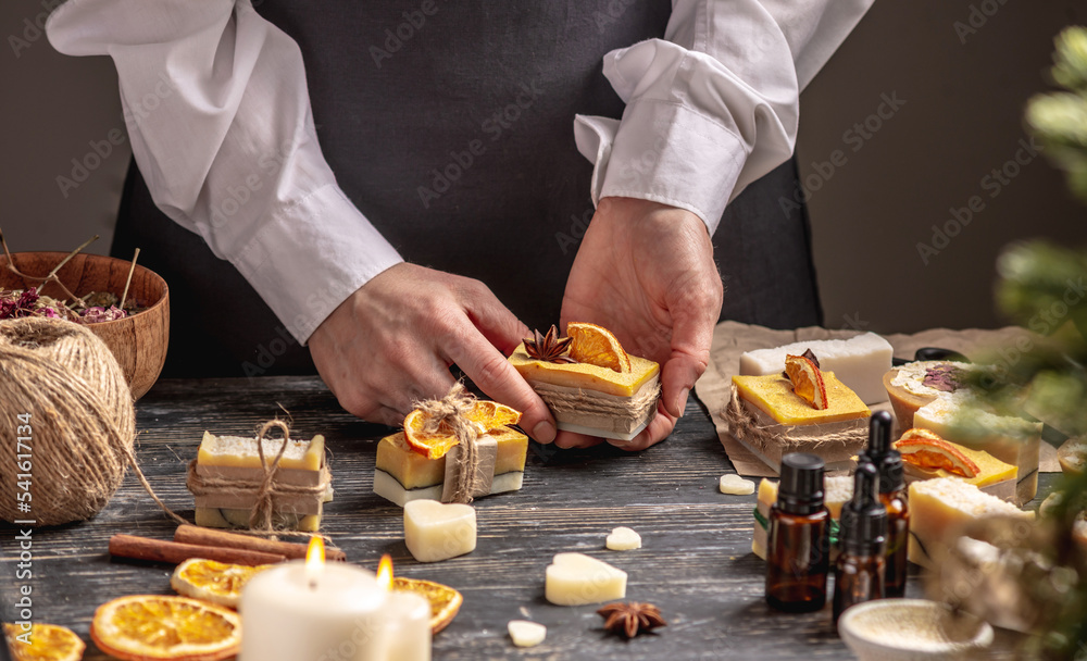 Woman is packing handmade natural soap as a gift for New Year and Christmas. Concept of preparing for holidays, hobbies, a cozy festive atmosphere Woman is packing handmade natural soap as a gift for New Year and Christmas. Concept of preparing for holidays, hobbies, a cozy festive atmosphere