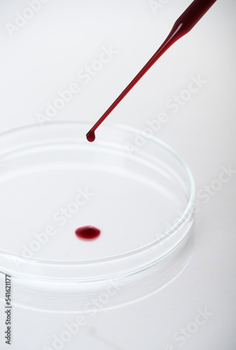 Close-up of pipette drop blood sample or red liquid on petri dish in the medical laboratory- analyzes and diagnostics concept- on white background