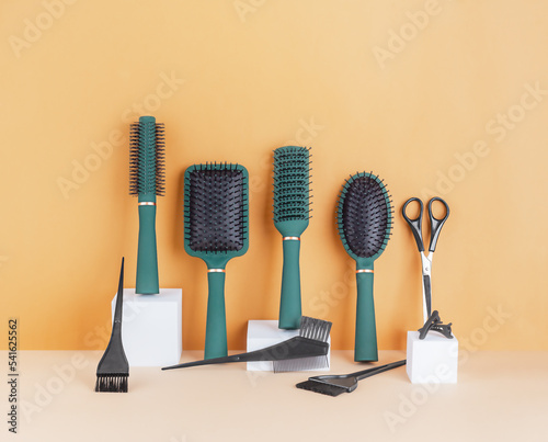 Set of various hairdressing accessories standing against a beige wall, front view, copy space.