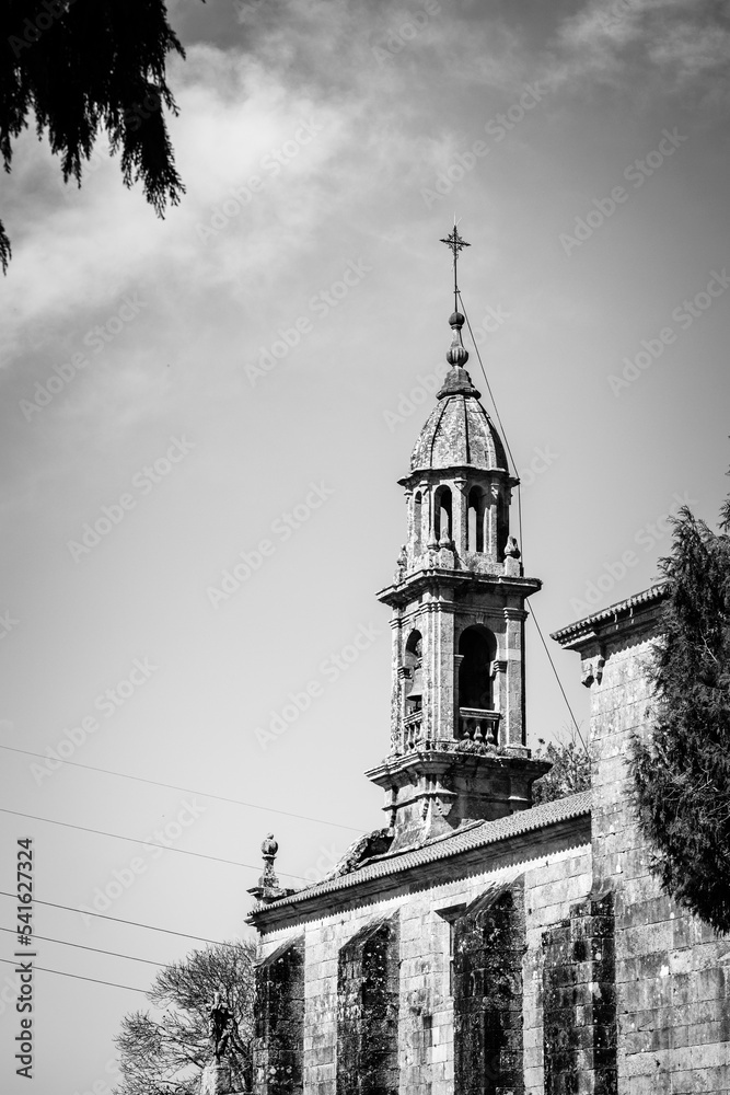 Black and white photograph of a stone bell tower of a small church in Galicia (Spain)