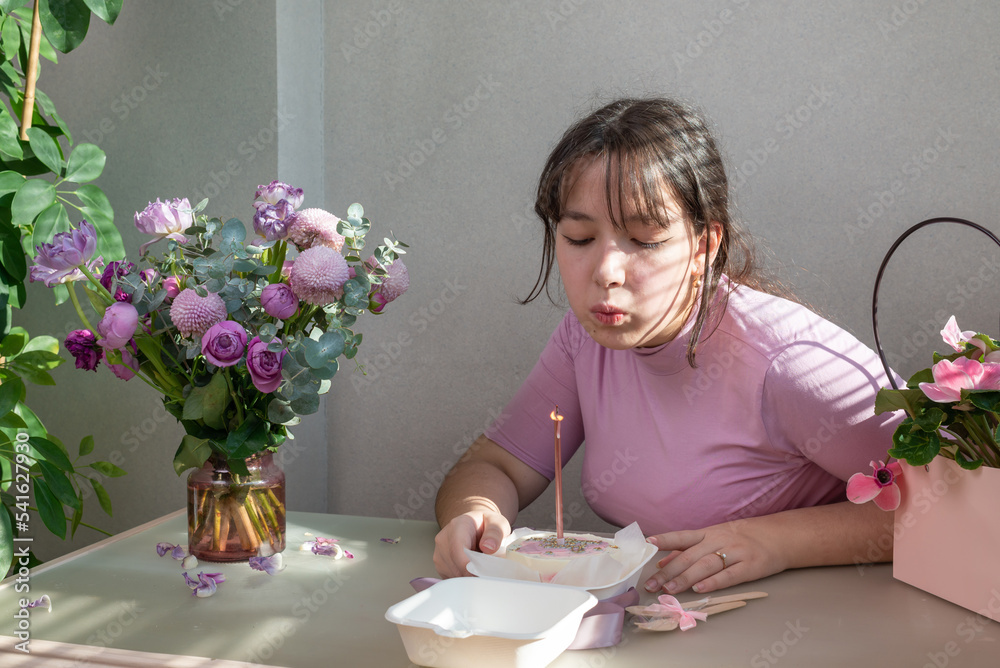 Portrait of a joyful girl making a wish while holding a birthday cake and blowing out a candle Portrait of a joyful girl making a wish while holding a birthday cake and blowing out a candle