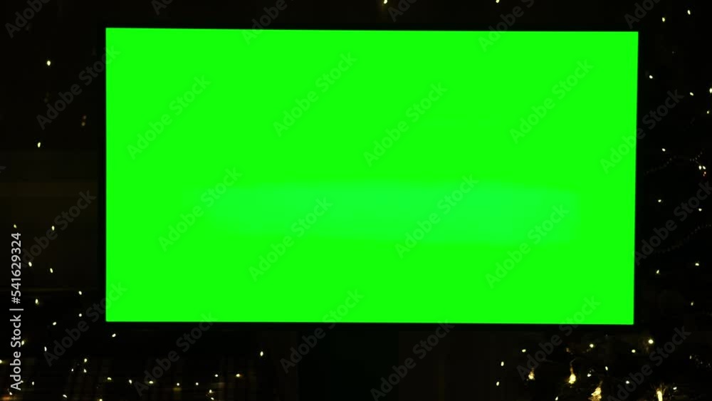 Big green screen of TV set mockup on black background with flashing