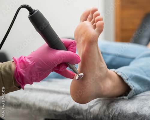 Fotografie A pedicurist treats the heels of a client using a machine with an abrasive disc in a beauty salon