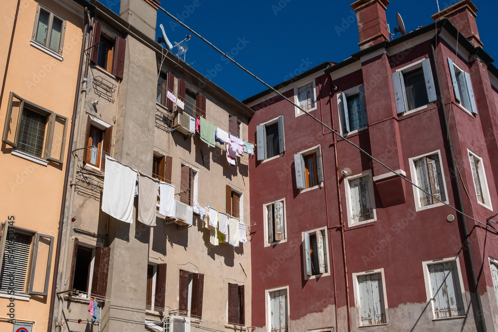 Typical view of the laundry hanging along a house facade at the edge of an alley in Italy