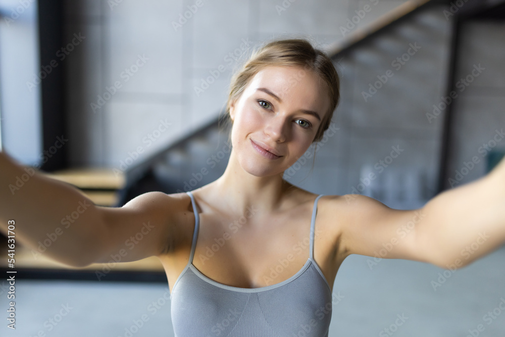 Young smiling sporty athletic fitness trainer instructor woman doing exercises do selfie shot on mobile phone sit on mat floor at home Young smiling sporty athletic fitness trainer instructor woman doing exercises do selfie shot on mobile phone sit on mat floor at home