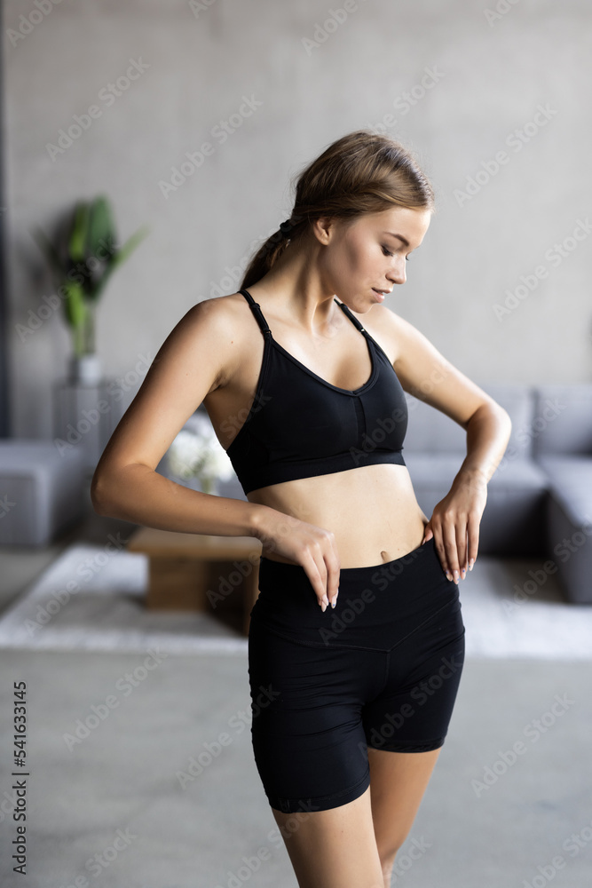 Portrait of an attractive woman wearing sportswear holding a yoga or fitness mat after working out at home.