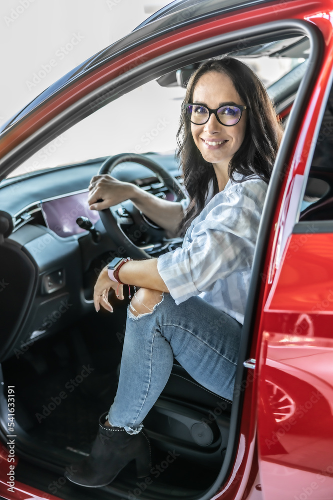 A satisfied customer sits in a new red car just before buying it A satisfied customer sits in a new red car just before buying it