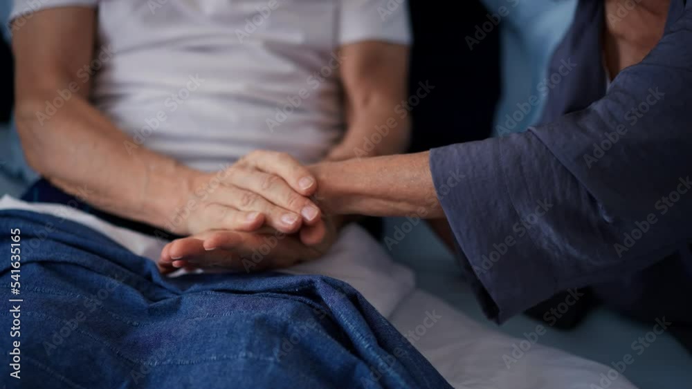 Senior couple in bed touching hands.