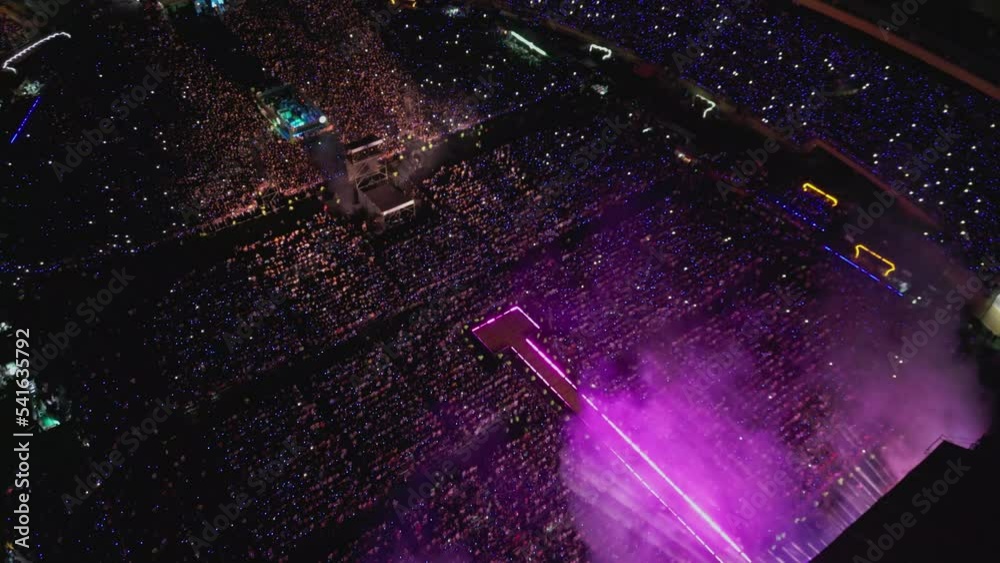 Large crowd at Bad Bunny evening concert in Felix Sanchez Olympic stadium, Santo Domingo. Aerial top-down orbiting