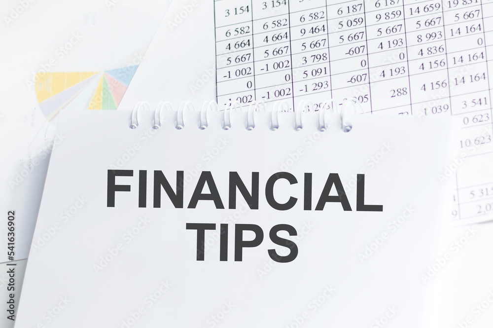 FINANCIAL TIPS . Text written on notepad with office tools and documents. FINANCIAL TIPS . Text written on notepad with office tools and documents.