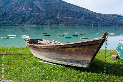 Una barca sulla riva erbosa del lago di Santa Croce in Alpago in una giornata di sole photo