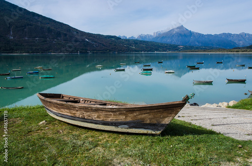 Una barca sulla riva erbosa del lago di Santa Croce in Alpago in una giornata di sole