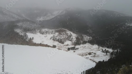 Life in challenging climatic conditions. A lakeside village surrounded by mountains and forests. A remote village during a snowstorm. A traditional way of life away from civilisation. Dark landscape.