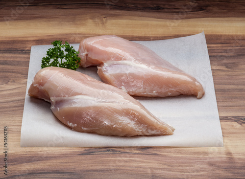 Skinless Chicken breasts with parsley on wax paper photo