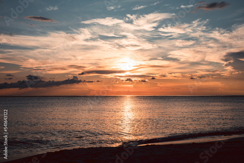 Scenic sunset in the Playa de la Cueva Beach  Cabo Rojo  Pedernales  Dominican Republic. Vibrant colors  sun above water falling in the sea. Romantic vacation atmosphere.