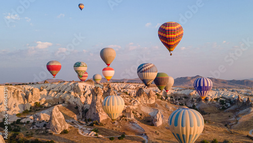 Cappadocia hot air balloons ride above rocky landscape of natural formations at sunrise in central Turkey