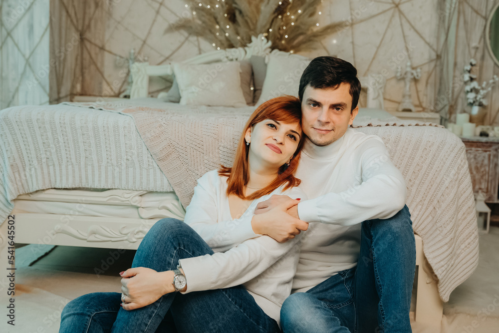 couple in the same white sweaters are hugging on the floor. Stock Photo ...