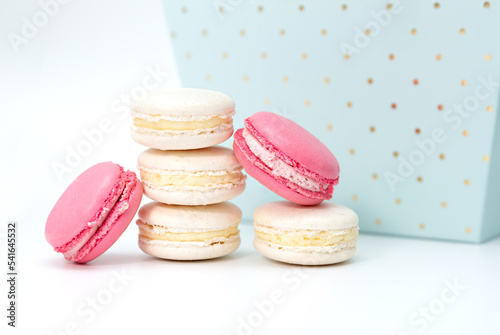 Several white and pink macaroon cakes on the background of a blue gift box