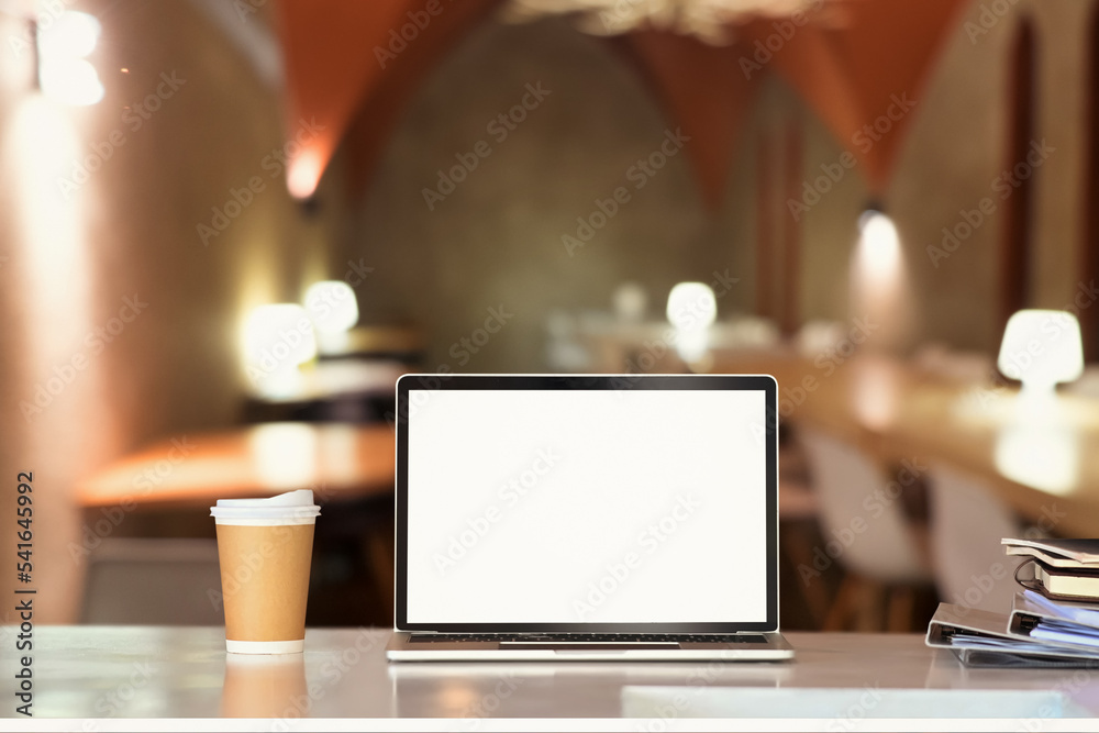 Laptop on white table with blurred restaurant in background. Blank screen for your product display or design montage Laptop on white table with blurred restaurant in background. Blank screen for your product display or design montage