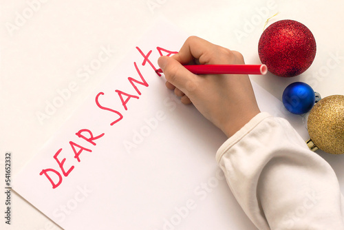 Human hand is writing letter to Santa at Christmas