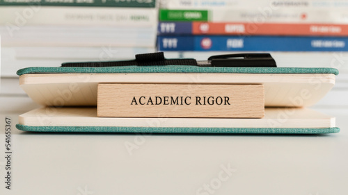 Academic Rigor writing on wooden surface. Book and wood concept. Education and work.