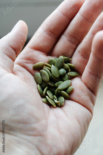 Pumpkin seeds peeled in a man's hand. Useful properties and vitamins for the diet of an adult in a handful of a natural product.