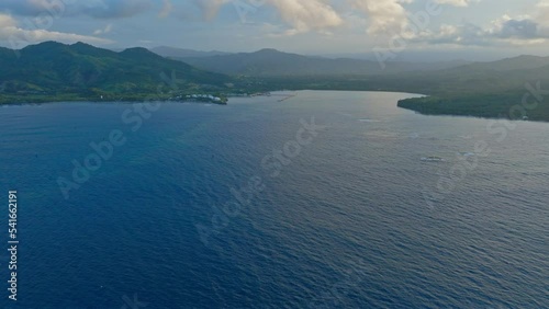 Calm and blue waters of Maimon Bay at dusk, Puerto Plata in Dominican Republic. Aerial forward photo