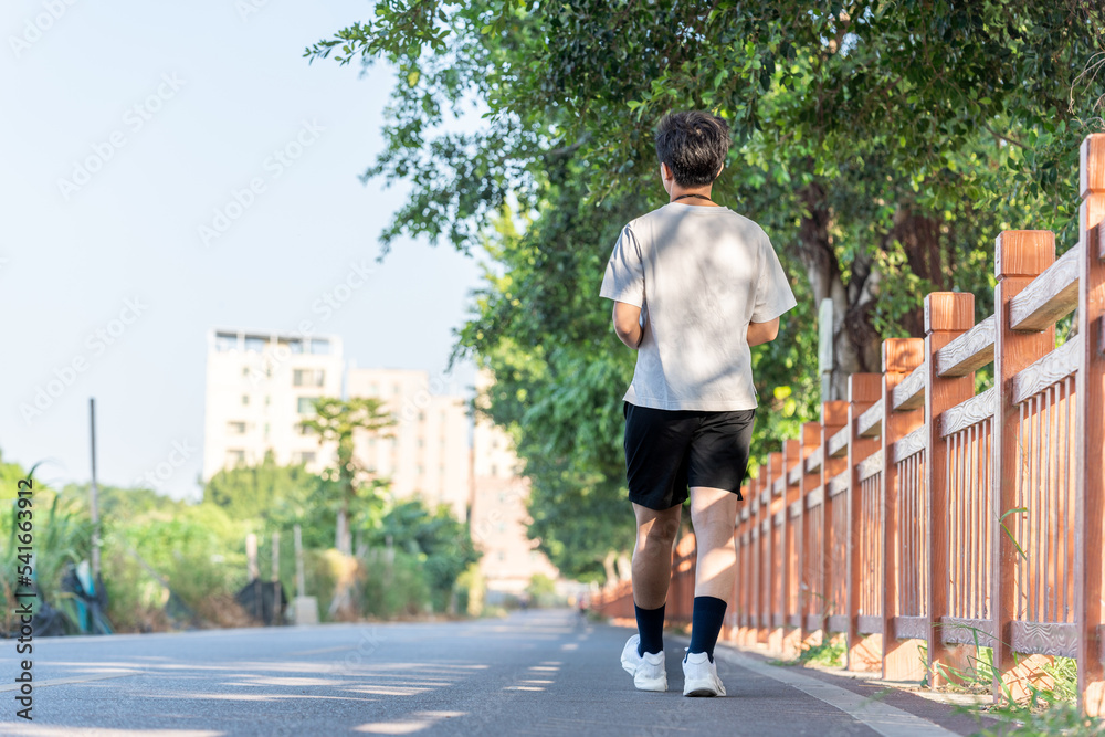 Back view of a young man walking outside. 