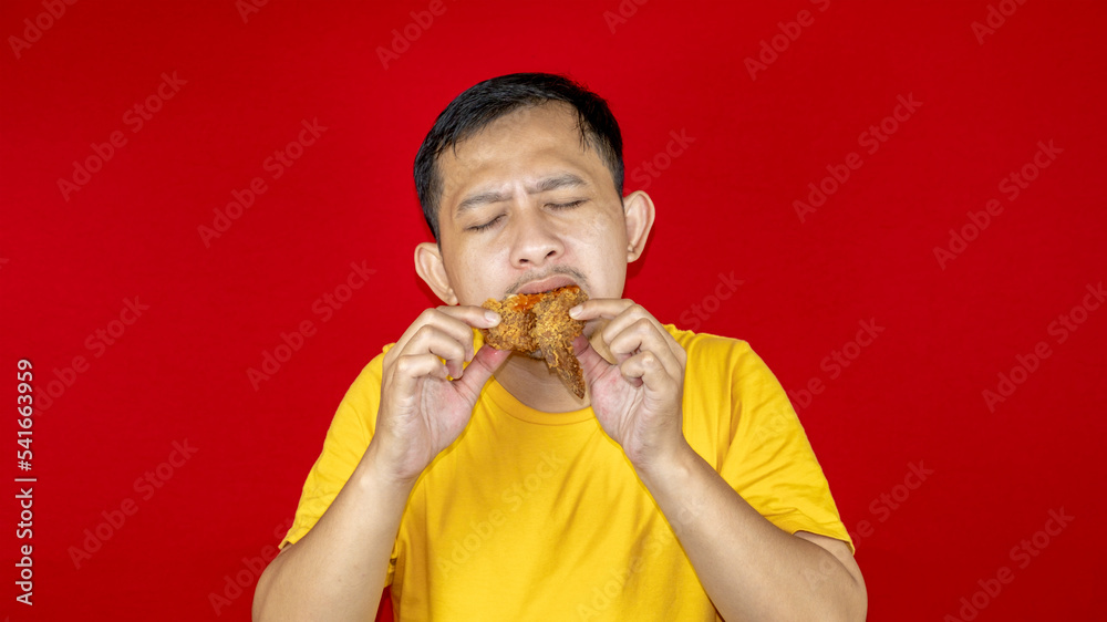 Portrait of Asian young man with fried chicken in hand. Portrait of Asian young man with fried chicken in hand.