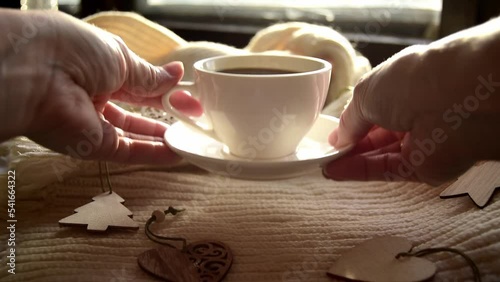 Hygge style. Woman's hand takes a mug of black coffee on a warm scarf with wooden Christmas toys. Vintage style, still life photo