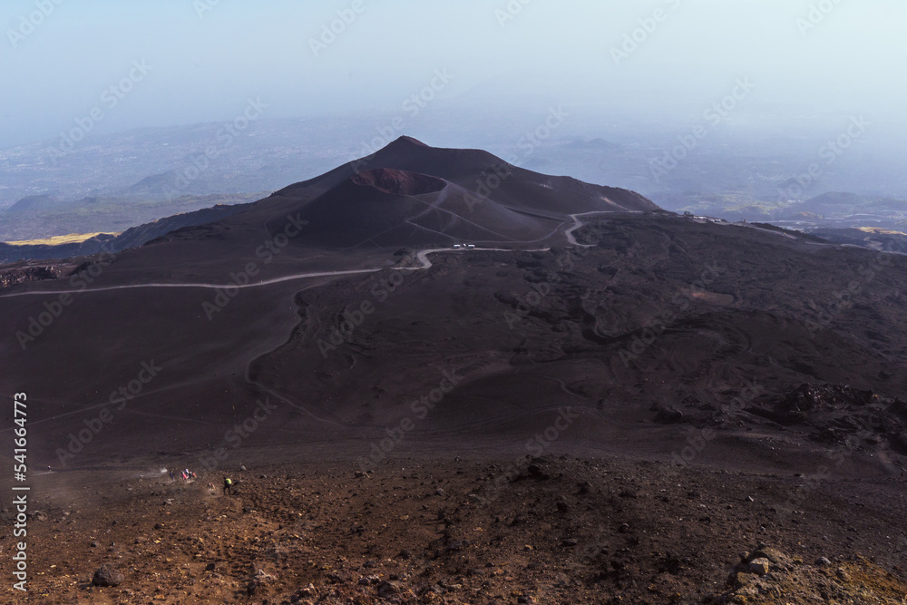 Restos de lava seca de coladas anteriores, frente al perfecto cráter del volcán Etna. 