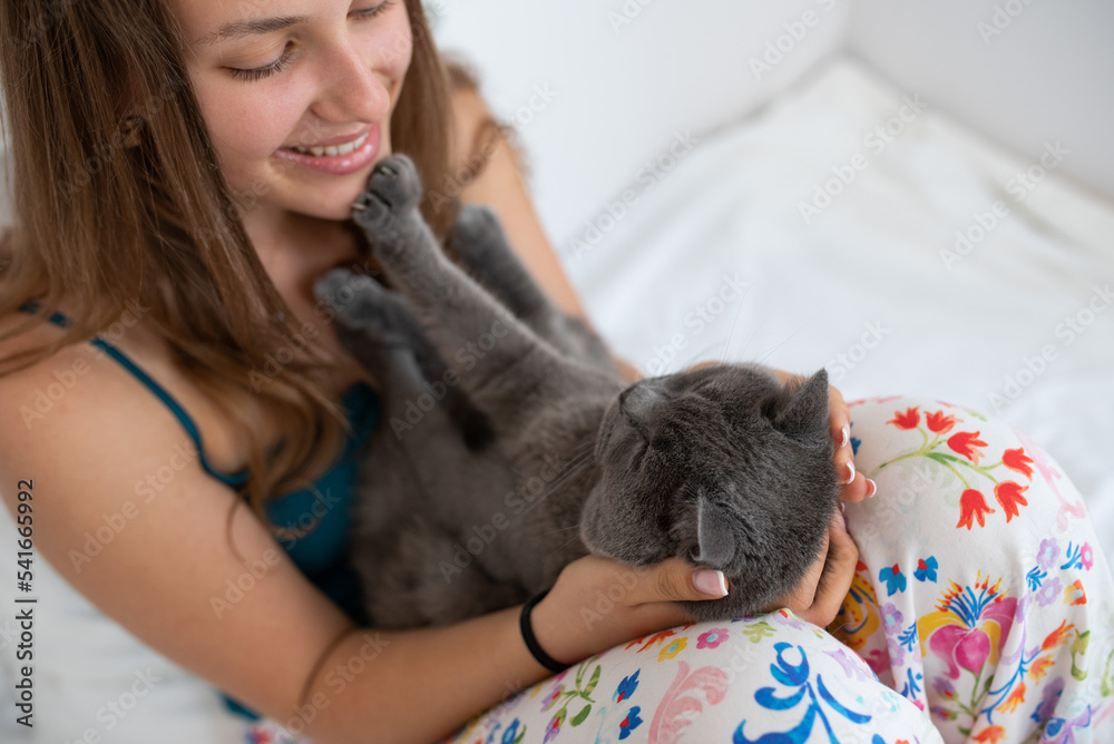 Young pretty woman playing with her British shorthair cat, his paw touching her face Young pretty woman playing with her British shorthair cat, his paw touching her face