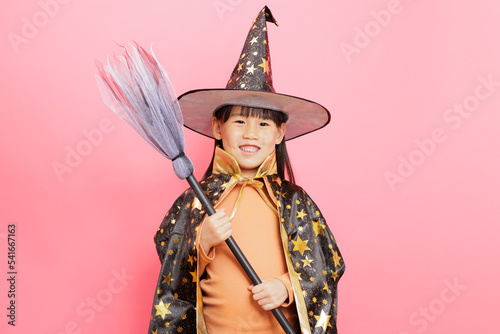 Happy Halloween! young girl with  witch costume gainst plain  background photo