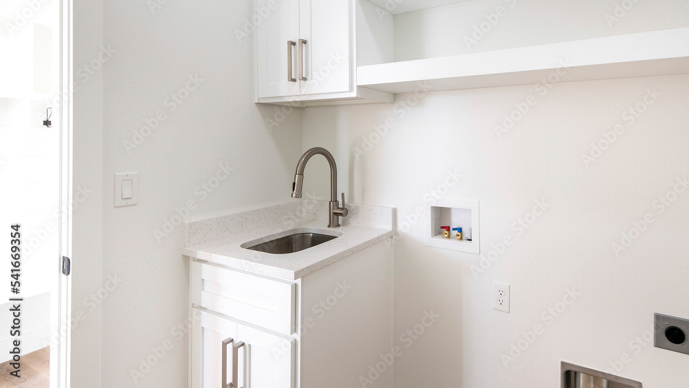 Panorama Empty laundry room with single vanity sink, wall cabinets and shelves Panorama Empty laundry room with single vanity sink, wall cabinets and shelves