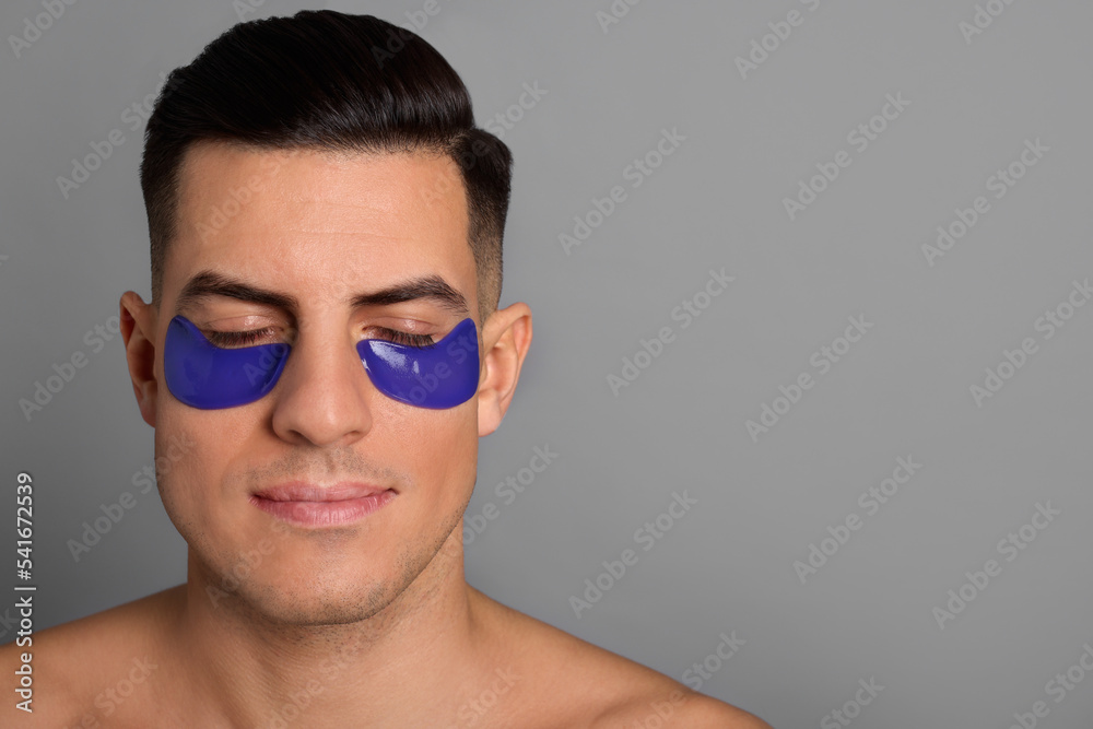 Man with blue under eye patches on grey background. Space for text Man with blue under eye patches on grey background. Space for text