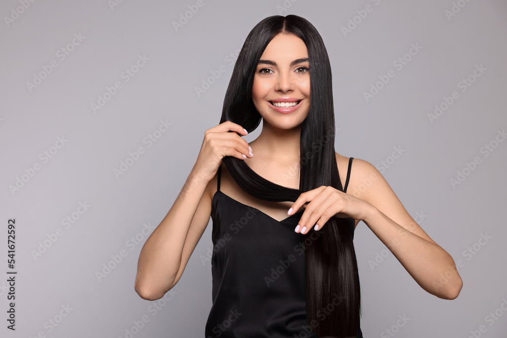 Portrait of beautiful young woman with healthy strong hair on light grey background, space for text Portrait of beautiful young woman with healthy strong hair on light grey background, space for text