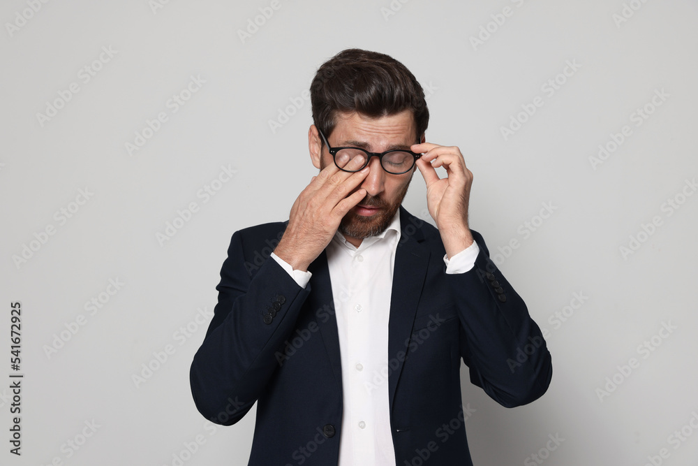 Man suffering from eyestrain on light grey background Man suffering from eyestrain on light grey background