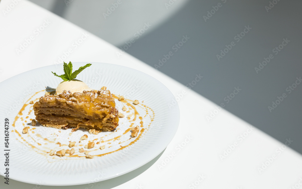 Walnut cake with custard cream and marmalade served with a vanilla ice cream ball ready to eat at a restaurant table.